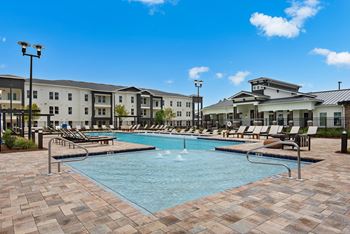 a swimming pool with lounge chairs and buildings in the background at The Enclave at Deer Moss Creek, Niceville